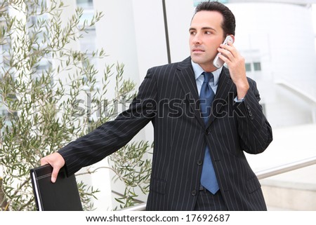 A young, handsome business man at the office building on cell phone