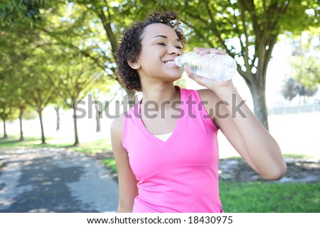 A young pretty african american woman jogger drinking water