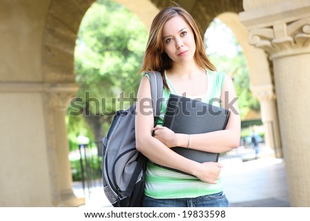 A pretty, young woman on the college campus walking to class