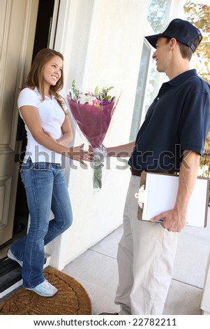 A delivery man giving flowers to pretty woman at home