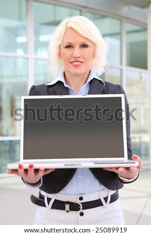 A pretty blonde business woman holding laptop computer
