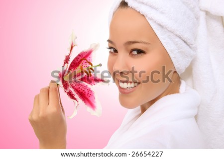 Beautiful young woman with pink lily in a bath robe and towel