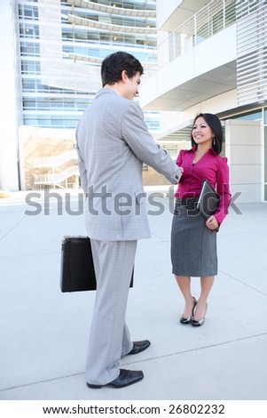 An attractive business man and woman team shaking hands at office building