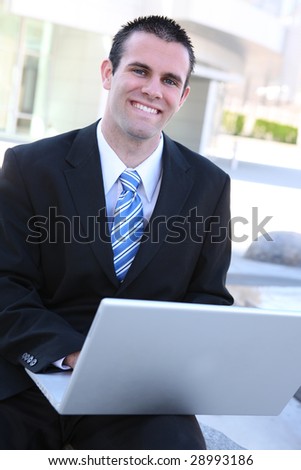 A young, handsome business man on laptop computer at office building