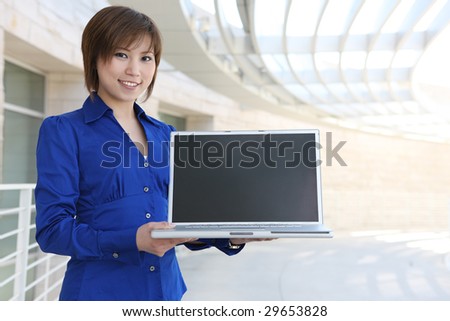 A young, beautiful asian business woman at office building with laptop computer