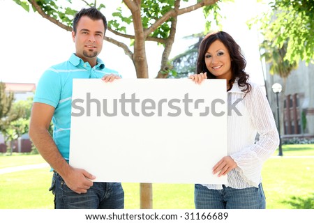 A young couple man and woman holding blank sign at school