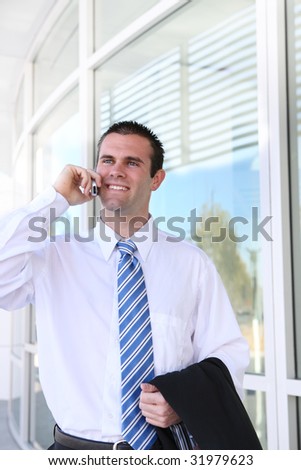 A young, handsome business man on the phone at office building