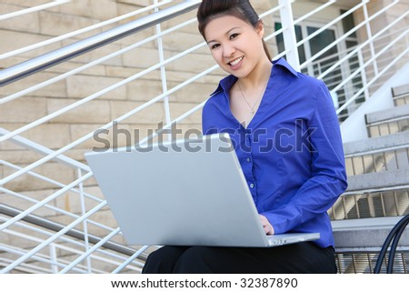 An asian business woman on stairs at office with laptop computer
