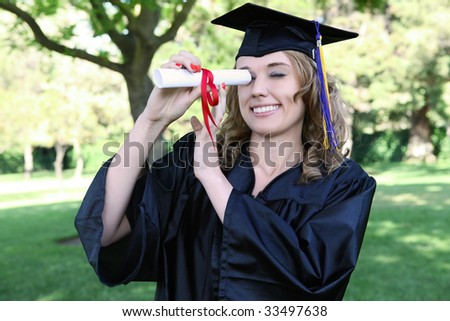 Pretty young woman at graduation looking through diploma