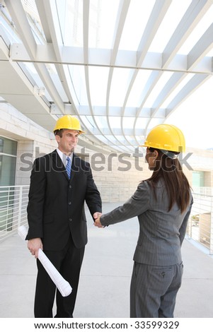 An attractive, diverse man and woman construction team shaking hands