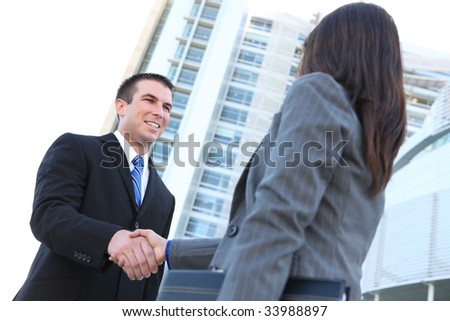 An attractive man and woman business team shaking hands at office building