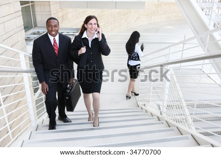Attractive diverse business man and woman team walking up stairs to work