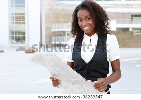 A young pretty african american business woman at office reading newspaper