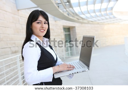 A pretty Indian business woman on laptop computer at office building