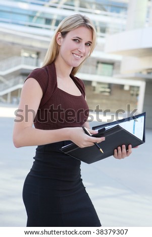 A beautiful blonde business woman at office building holding notebook