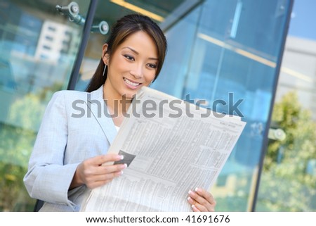 A young attractive asian business woman reading  newspaper