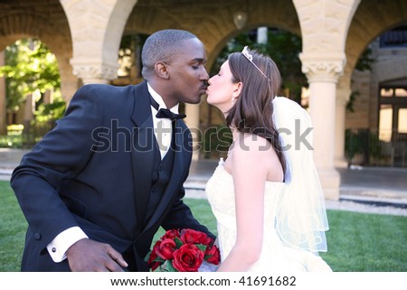 A young and attractive man and woman wedding couple kissing outside church
