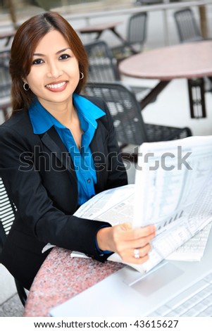 A pretty asian business woman reading the newspaper at office building