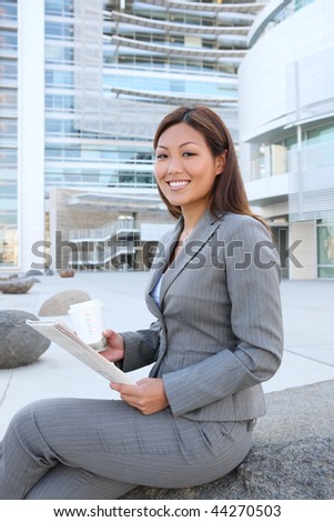 A young asian business woman reading the newspaper at office building