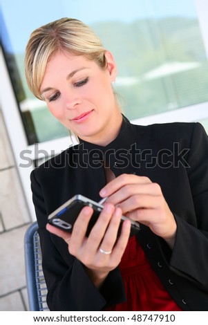 A pretty blonde business woman texting at office building
