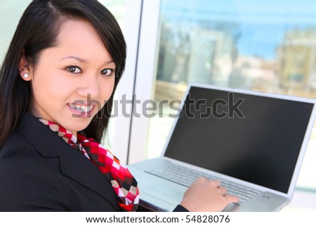 A young pretty asian business woman on laptop computer at office