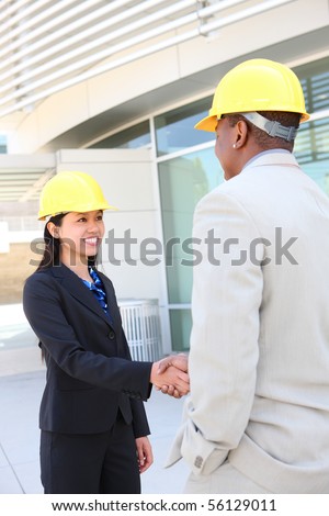 An attractive man and woman architect team on construction site handshake