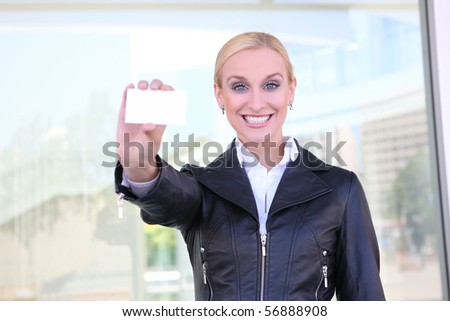 Pretty young blonde business woman giving her card at office building