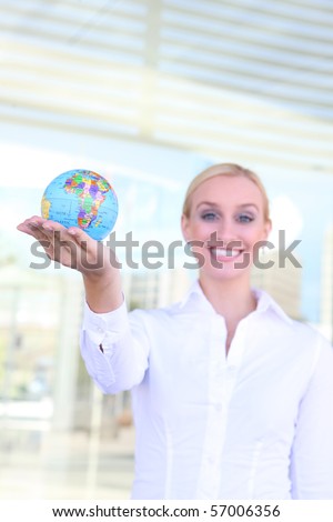 A beautiful young blonde woman holding a globe at office building