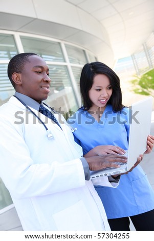 stock photo : An ethnic medical man and woman team outside hospital on laptop computer
