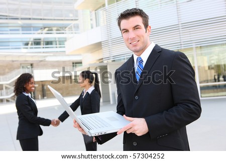 A handsome business man with laptop computer and team in background