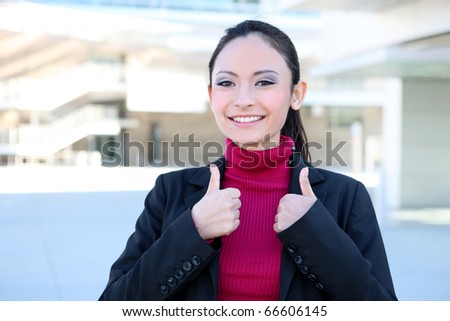 A pretty young caucasian business woman at office with thumbs up celebrating success