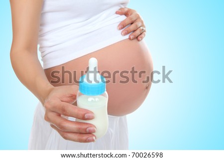 A pregnant woman mother holding baby bottle with belly exposed