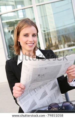A pretty business woman reading the newspaper outside her company