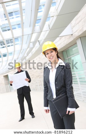 A pretty woman asian architect on work site with male co-worker in background