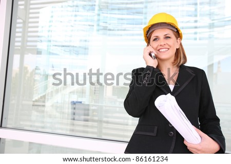 A woman construction manager on a building site talking on phone.