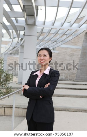 A pretty Chinese business woman smiling outside office building