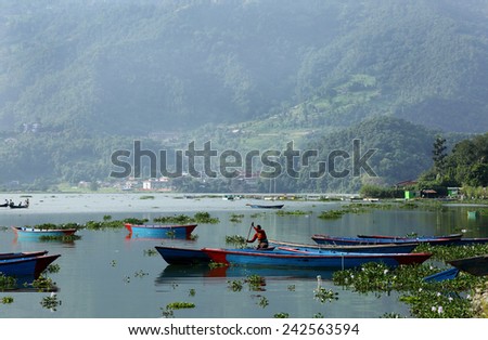 POKHARA, NEPAL-AUGUST 22: A boat woman taking out her boat in the vast Phewa Lake on August 22, 2014, Pokhara, Kathmandu, Nepal.  Phewa lake is a tourist spot located at an altitude of 742 m