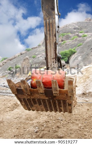 An oil drum inside a bucket of excavator transported in a granite mine