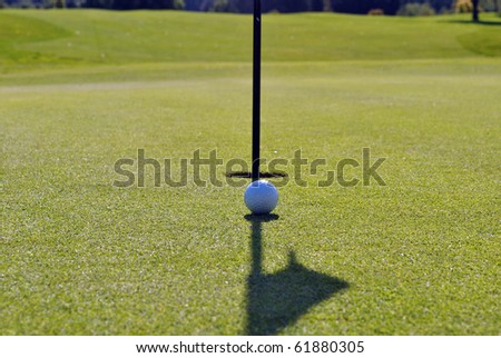 golf ball running in the line of the shadow of the flag