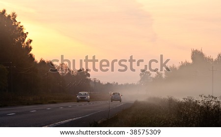 Sun rising over road partially hidden by a fog