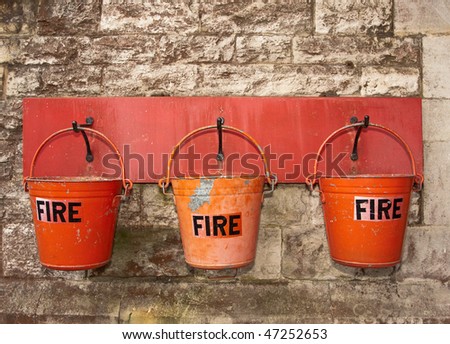 A row of three red fire buckets hung on the wall of an old railway station