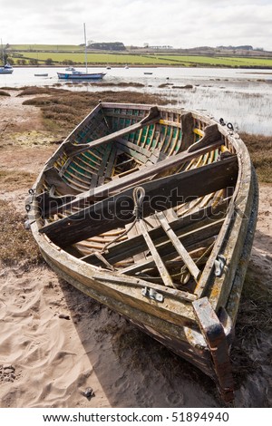 An old rowing boat on the beach by the estuary in need of repair