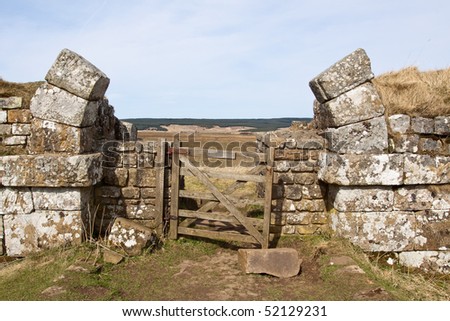 An incomplete broken stone arch through Hadrian\'s Wall as an entrance to the Northumberland landscape beyond