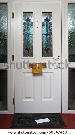The inside of a front door with a letter in the in flap and on the doormat