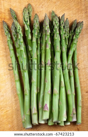 A bunch of asparagus tips on a wooden chopping board