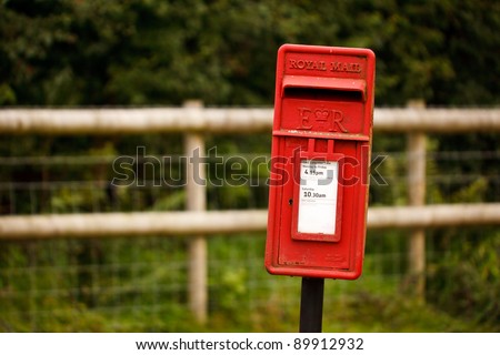 A red Royal Mail post box on a post in a country location