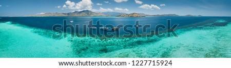 Aerial drone panoramic shot ocean, Komodo background. Transparent turquoise water of the Pacific ocean with the boats taken for tourist reasons. Komodo National Park, Indonesia.