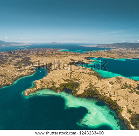 Bays, savanna lands, ocean. Komodo. Aerial shot. Spectacular panoramic view from above the stunning bays and savanna territory of Komodo National Park. Indonesia. Heritage Site. Overview drone shot.