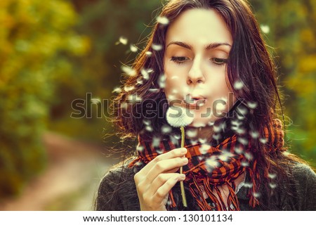 Girl Blowing On White Dandelion In The Forest