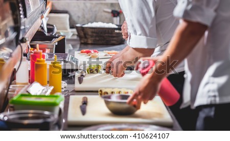 male cooks preparing sushi in restaurant kitchen